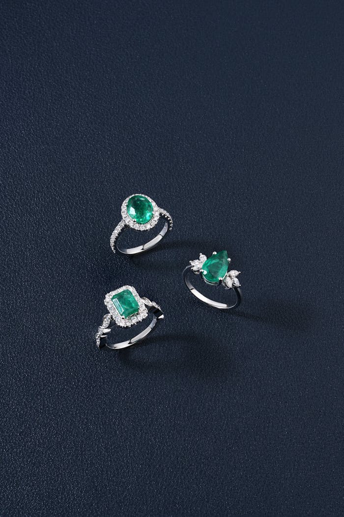 Showcasing three exquisite emerald and diamond rings against a dark backdrop, perfect for jewelry enthusiasts.